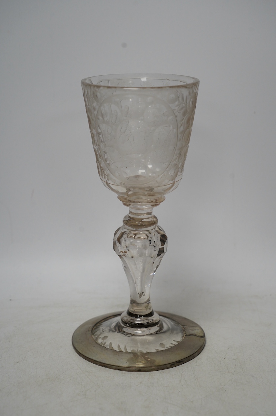 A Victorian engraved tall stemmed wine glass with white metal mounted foot rim, 22cm high. Condition - fair to good